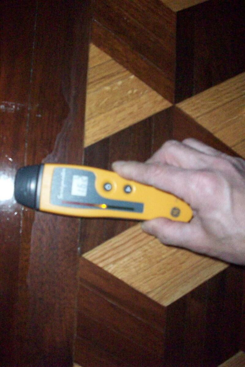 A hand pressing a wood moisture meter against wood