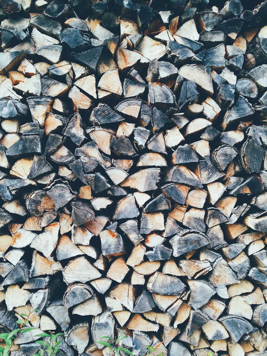 A wall of split firewood with faded gray ends
