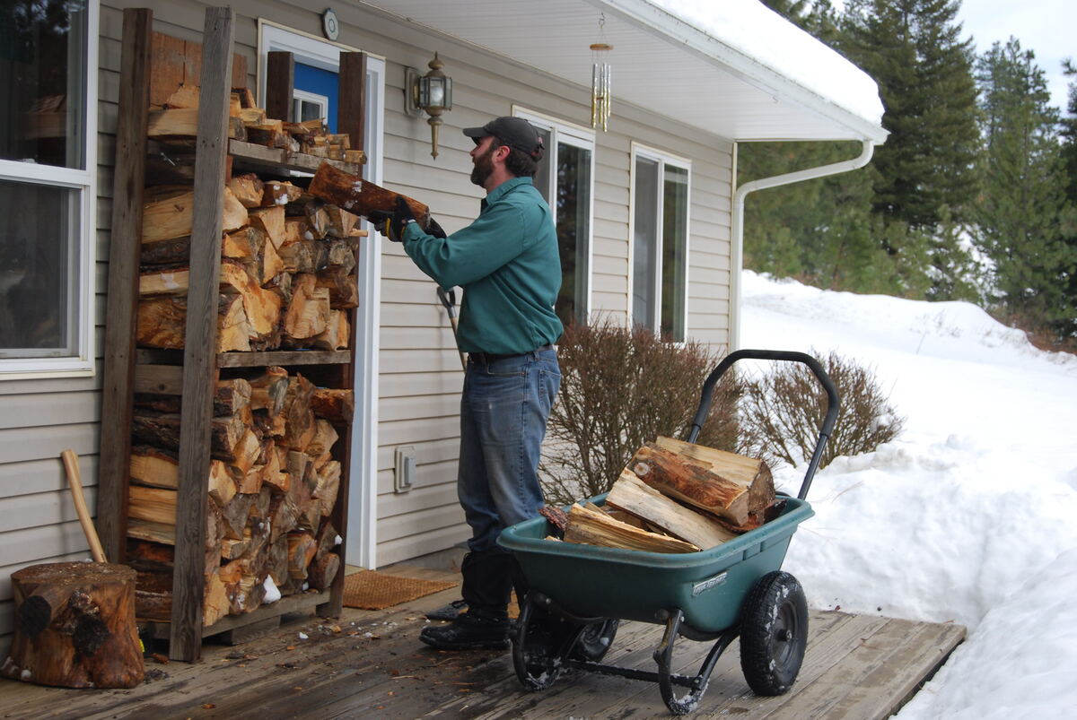 A man carrying firewood from a woodshed